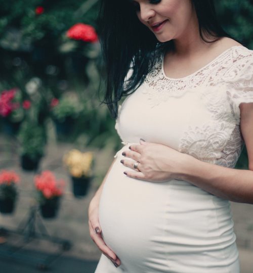 close-up-photo-of-pregnant-woman-in-white-dress-holding-her-2100341